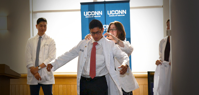 man recieving his white coat during the White Coat Gala